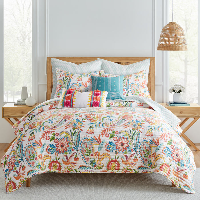 Colorful floral bedding ensemble with decorative pillows in a bright bedroom setting.