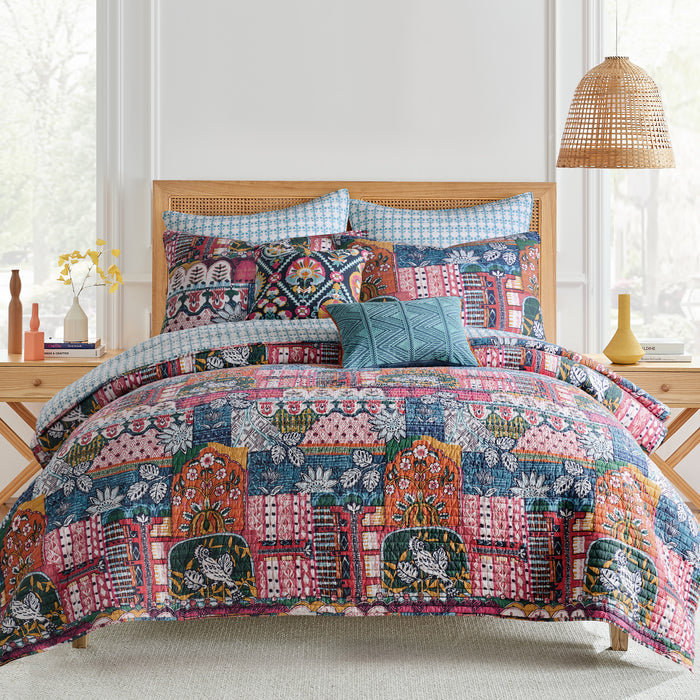 Roshita Crewel Diamond Pillow displayed on a colorful bedding set with intricate patterns and textures.