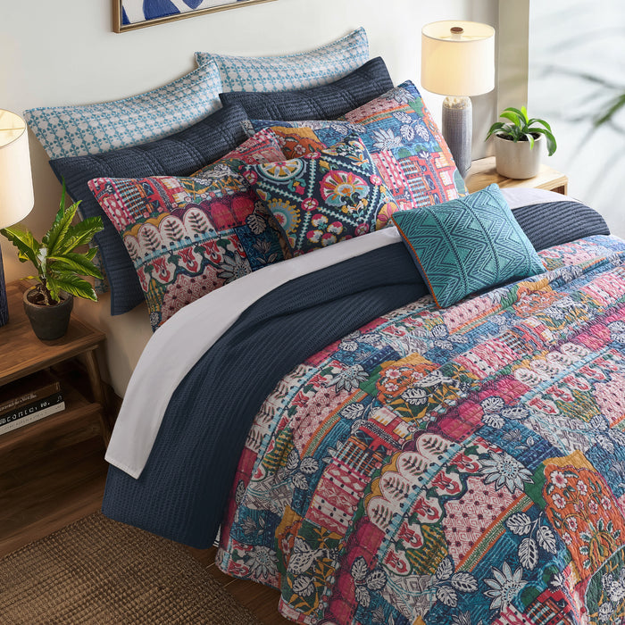 Roshita Quilt Set displayed on a bed with vibrant boho style patchwork design and colorful shams.
