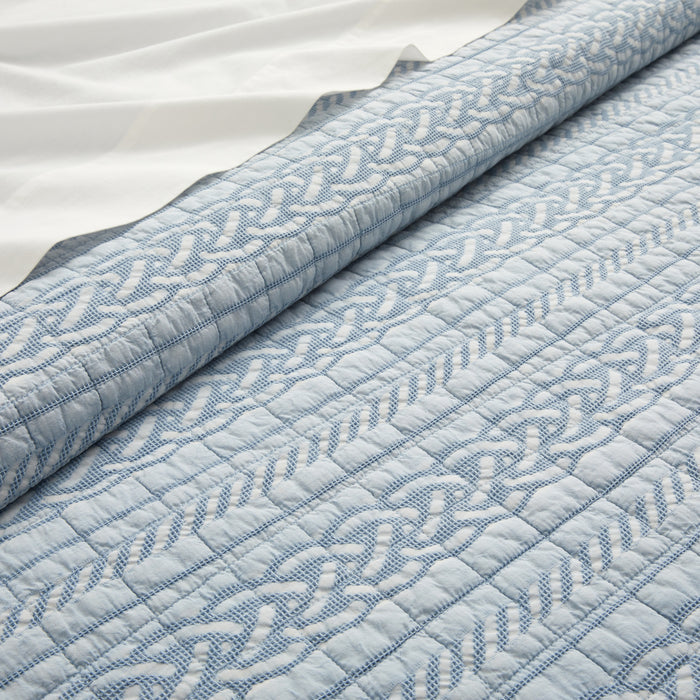 Close-up of a quilt with a textured pattern on a white background
