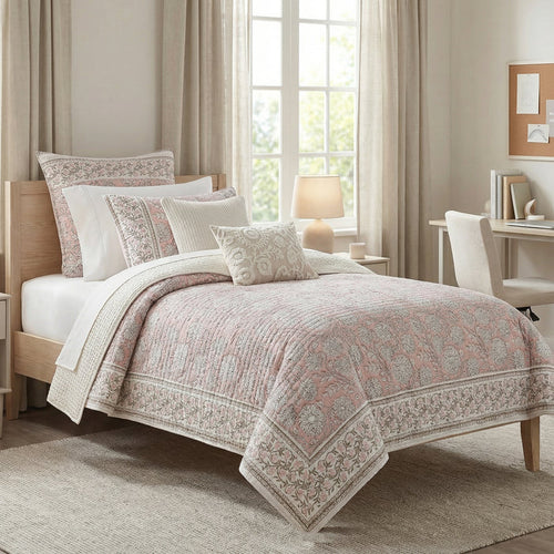 Bedroom with a bed covered in a patterned comforter, pillows, and a lamp on a nightstand.