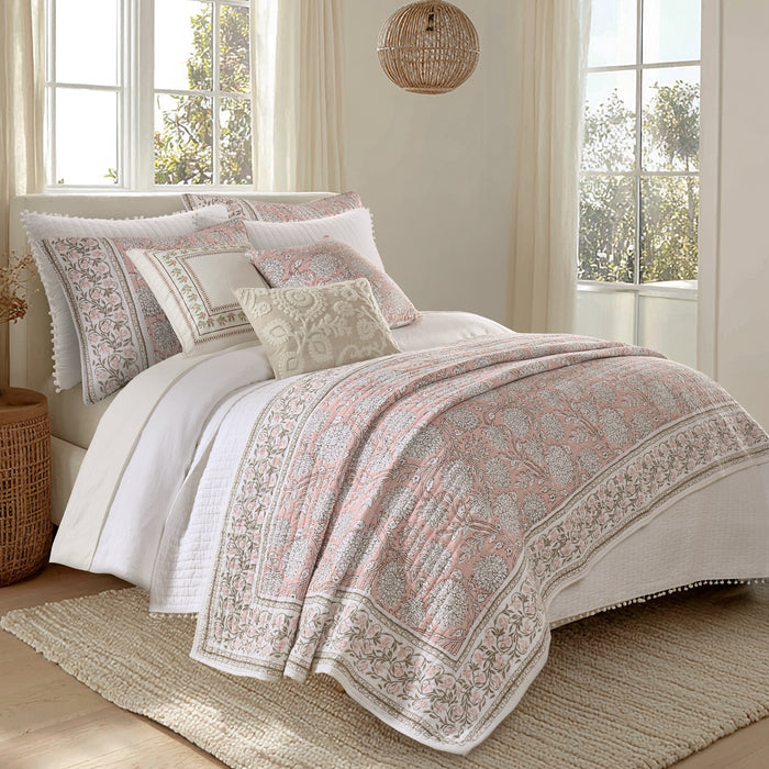 Patterned bedding set on a bed in a bright room with large windows.