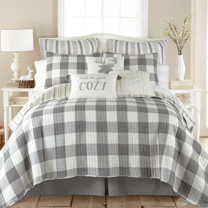 Bed with gray and white checkered comforter and pillows in a bedroom setting.
