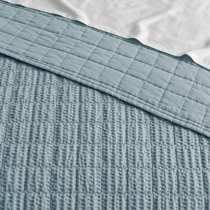 Textured blue blanket with a checkered pattern on top