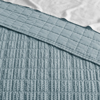 Textured blue blanket with a checkered pattern on top