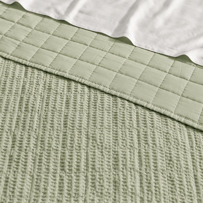 Close-up of a textured green fabric with a checkered pattern on a white background