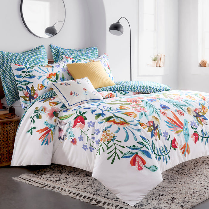 Colorful floral bedding set on a bed in a bright bedroom.