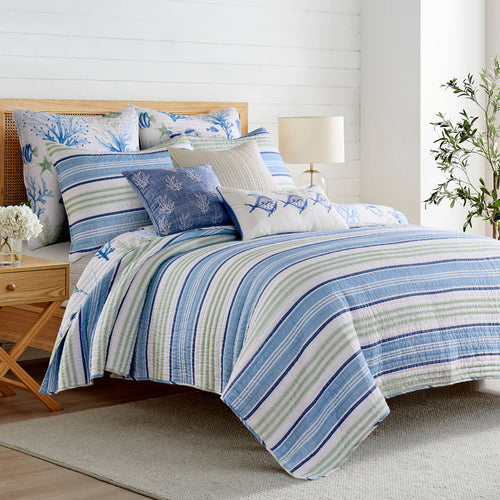 Bedroom with a bed covered in blue and white striped bedding and patterned pillows.