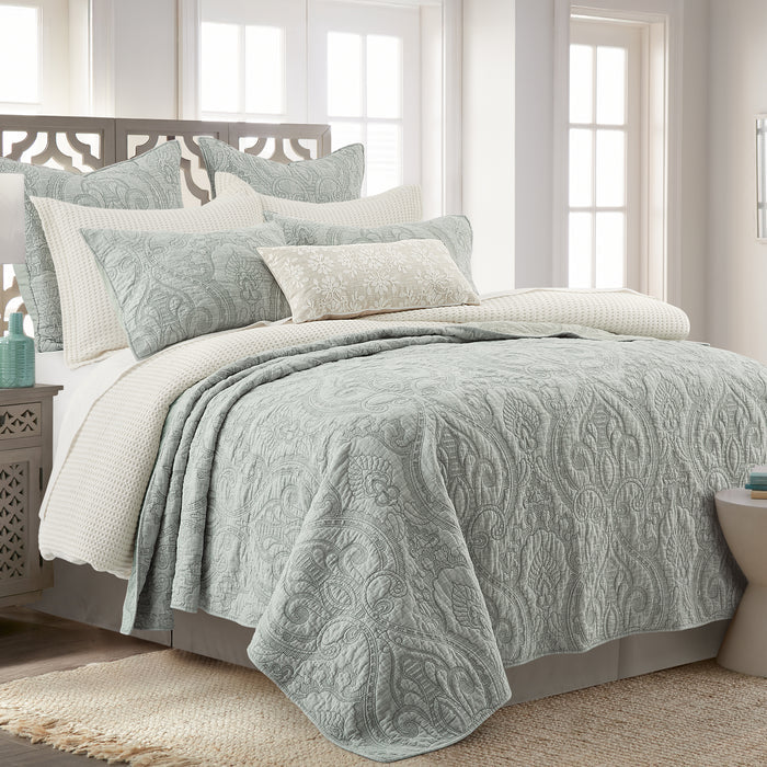 Bed with green patterned bedding in a bright bedroom