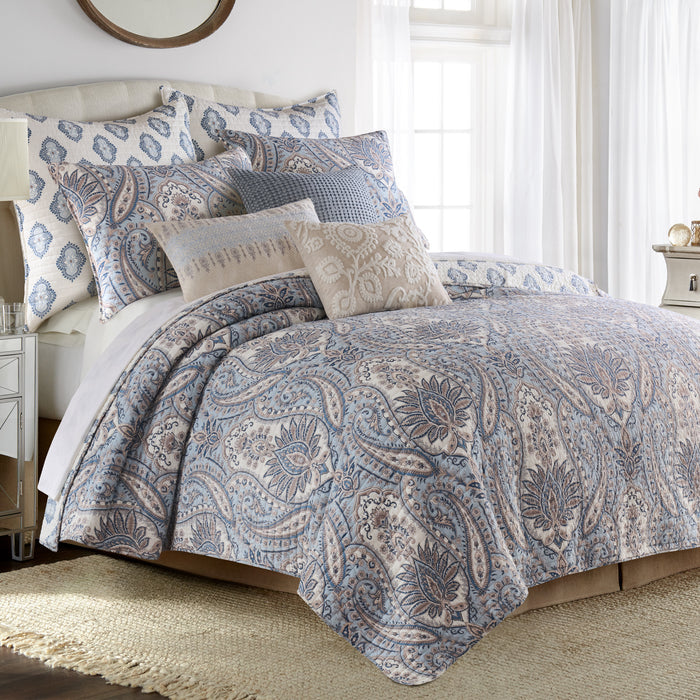 Bed with paisley patterned bedding and pillows in a bedroom setting.