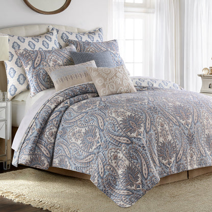Bed with paisley patterned bedding and pillows in a bedroom setting.