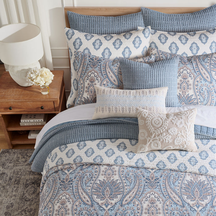 Bed with patterned bedding and pillows in a bedroom setting