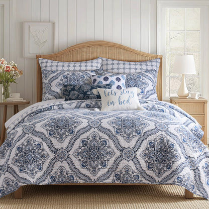 Lentana Navy Quilt Set displayed on a bed with intricate medallion pattern in navy and white, accompanied by decorative pillows.