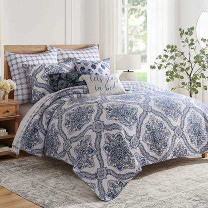 Lentana Navy Quilt Set featuring intricate medallion pattern on bed with coordinating pillows and shams.