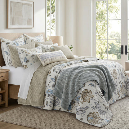 Bedroom with floral bedding and pillows in a bright room