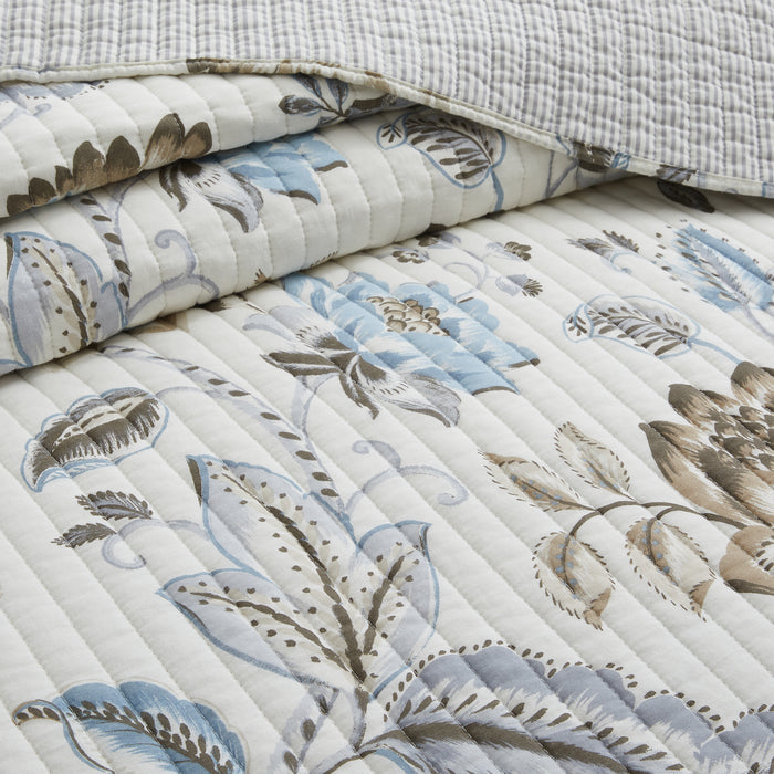 Floral patterned quilt with blue and brown design on a white background