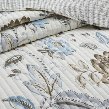 Floral patterned quilt with blue and brown design on a white background