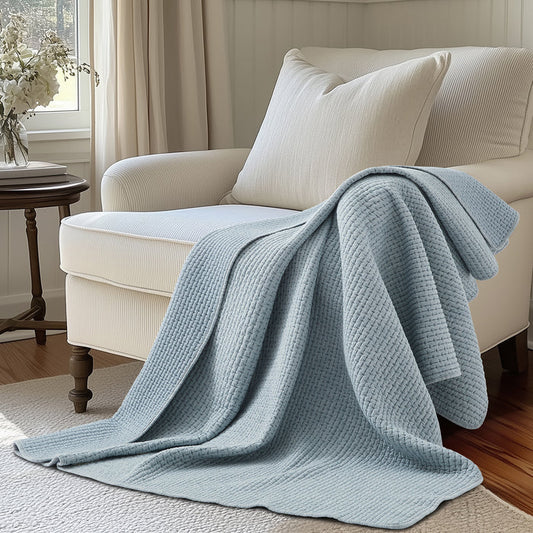 Pick-Stitch Artisan Quilted Throw draped over a white chair, showcasing its cozy quilted texture and light blue color.