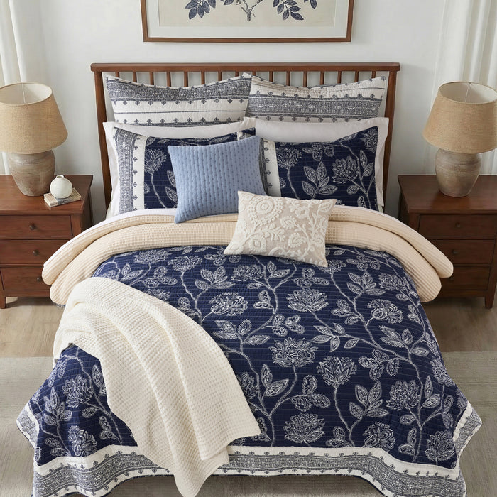 Bedroom with floral bedding and matching pillows on a bed.