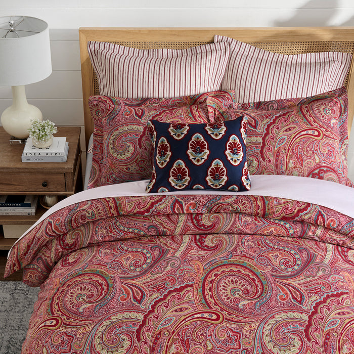 Spruce Comforter Set featuring a vibrant paisley print in red and gold, complemented by striped and decorative pillows.
