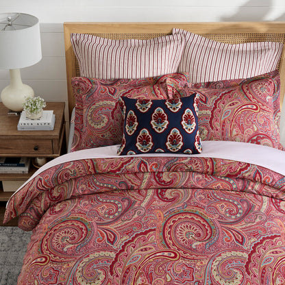 Spruce Comforter Set featuring a vibrant paisley print in red and gold, complemented by striped and decorative pillows.