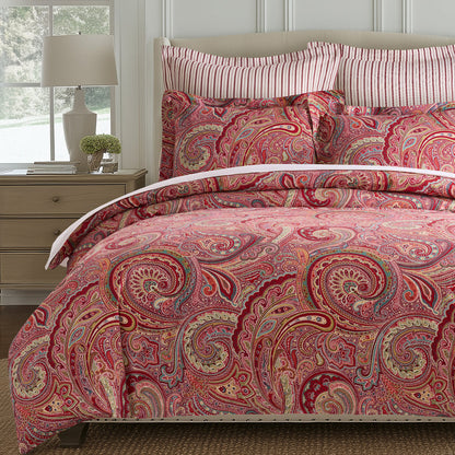 Spruce Comforter Set featuring a vibrant paisley print in red and gold, with coordinating striped pillowcases.