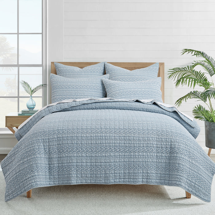 Blue patterned quilt set with matching pillows in bright bedroom