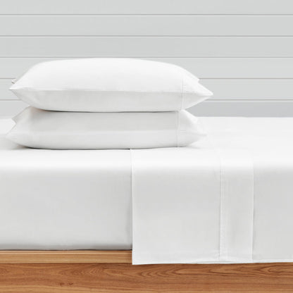 White Sateen Fitted Sheet displayed with two pillows on a bed, showcasing soft cotton and luxurious texture.